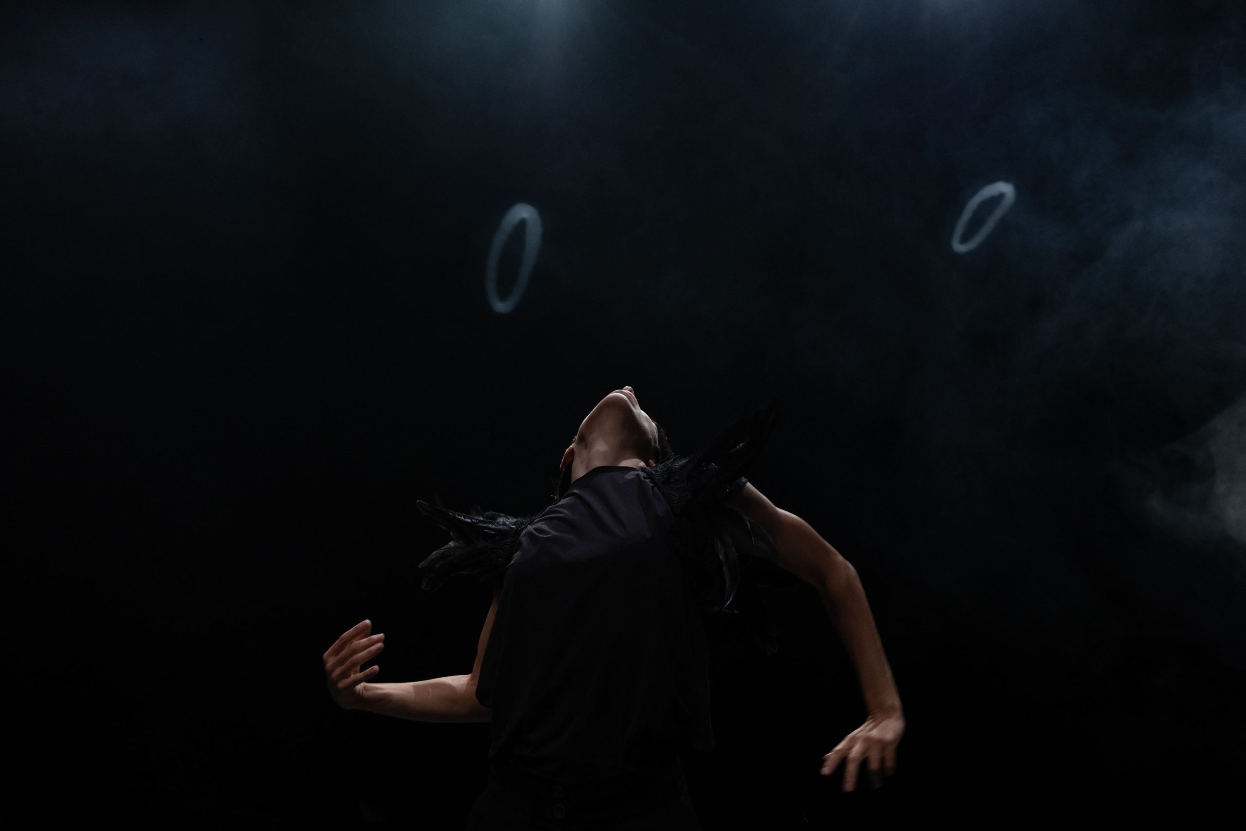 performer in scena con la schiena all'indietro e il viso rivolto verso l'alto. Attorno a lei dei cerchi fi fumo.